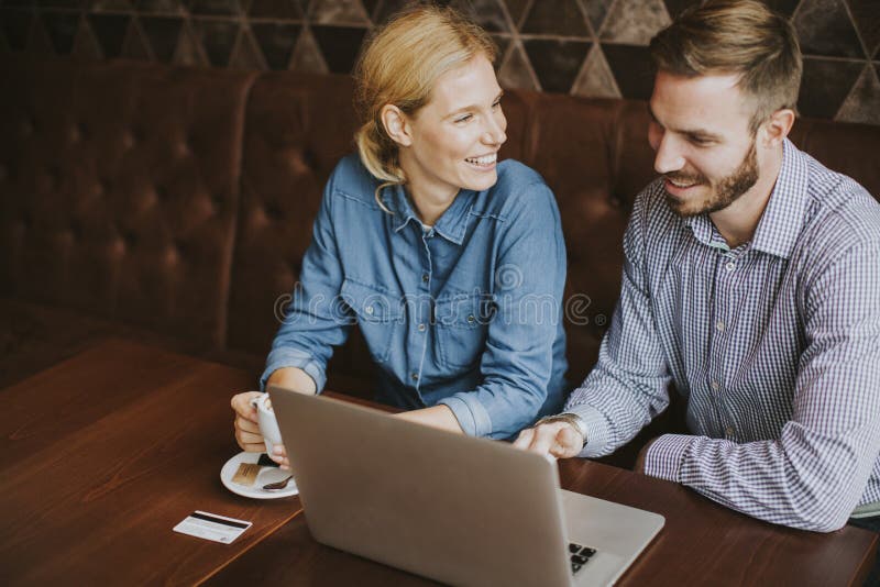 Couple buying online with credit card and laptop in a coffee sho stock photos Couple buying online with credit card and laptop in a coffee sho stock photos