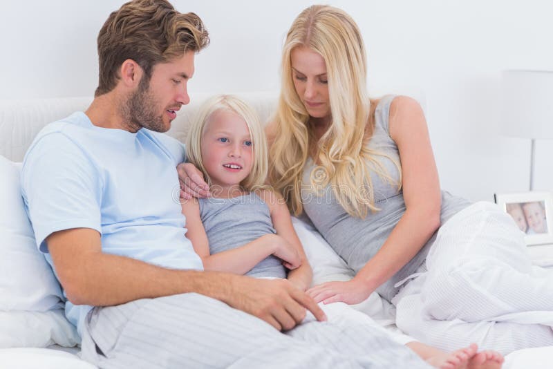 Couple chatting with their daughter in bed