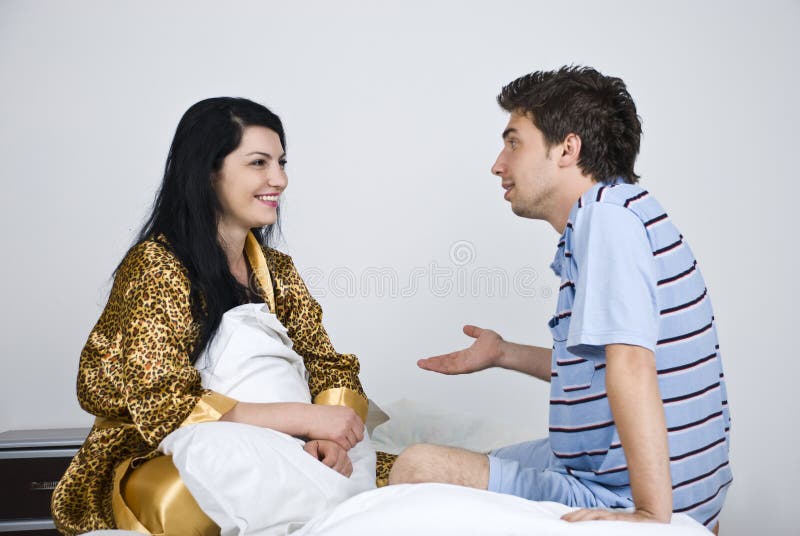 Young couple having an conversation in their bed , the man explaining something her and gesticulate with his hand,see more in. Young couple having an conversation in their bed , the man explaining something her and gesticulate with his hand,see more in