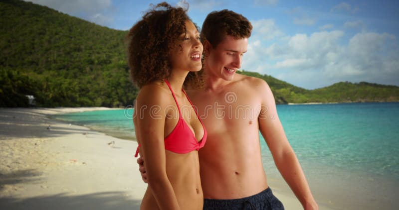 Couple de jeunes adultes jouant dans l'eau de plage. femme noire en bikini jouant avec un célibataire mâle blanc sur la plage des banque de vidéos
