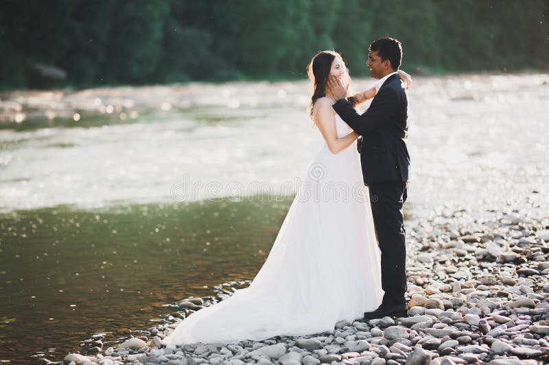 Couple de mariés sur la nature se serrent dans ses bras. belle mannequin fille en robe blanche. homme en costume image libre de droits
