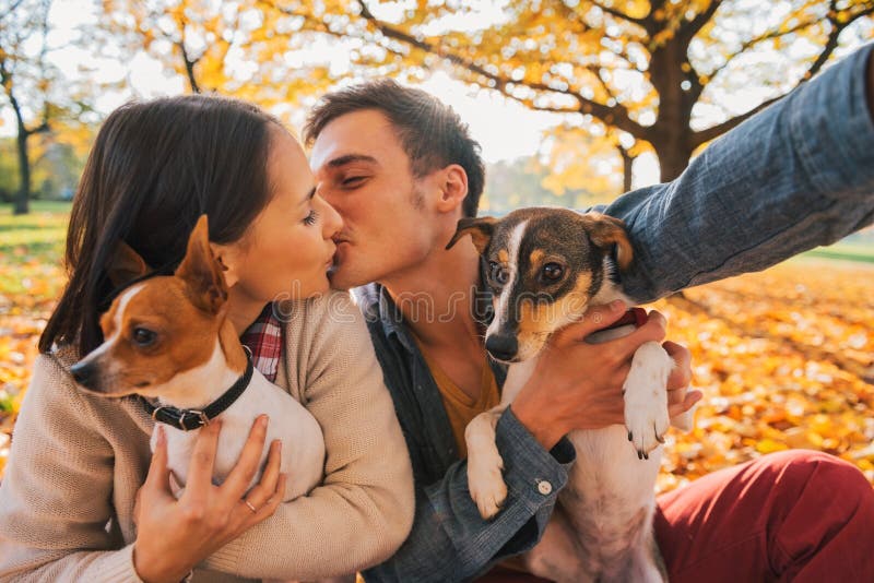 Couple with dogs making selfie while kissing in autumn park stock photos Couple with dogs making selfie while kissing in autumn park stock photos