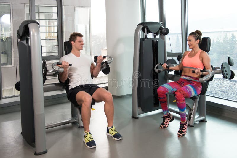 Couple Doing Exercise For Biceps In Gym