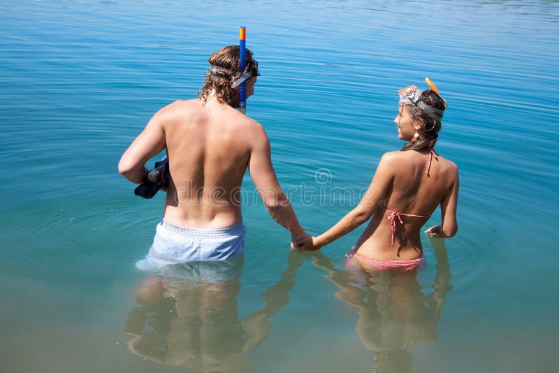 Young couple in love goes into the sea holding hands. Young couple in love goes into the sea holding hands