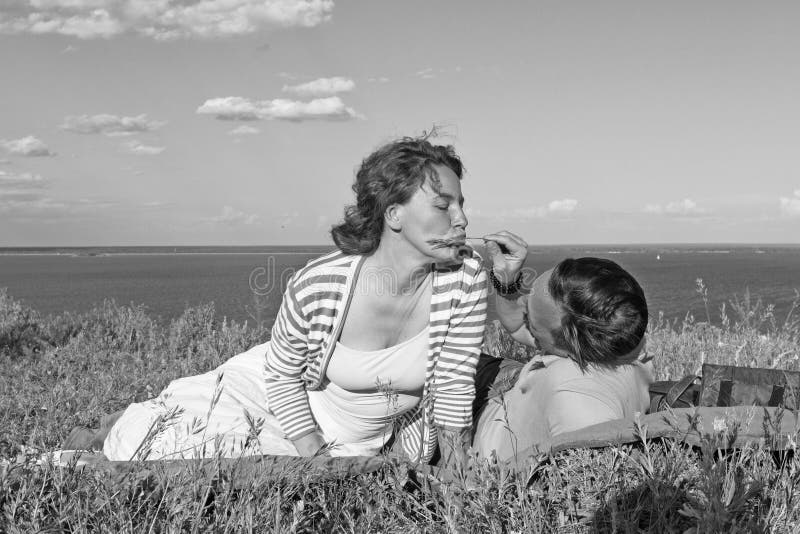 Couple dressed casual lying together on the lawn in summer grass on the river bank under blue sky and clouds royalty free stock photography Couple dressed casual lying together on the lawn in summer grass on the river bank under blue sky and clouds royalty free stock photography