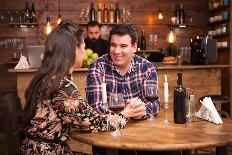 Couple drinking red wine and sharing a beautiful moment in a hipster pub. royalty free stock photos Couple drinking red wine and sharing a beautiful moment in a hipster pub. royalty free stock photos