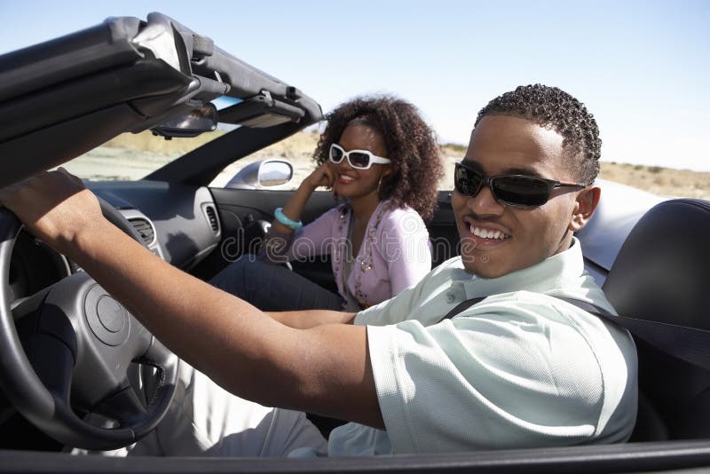 Couple Driving Convertible On Desert Road