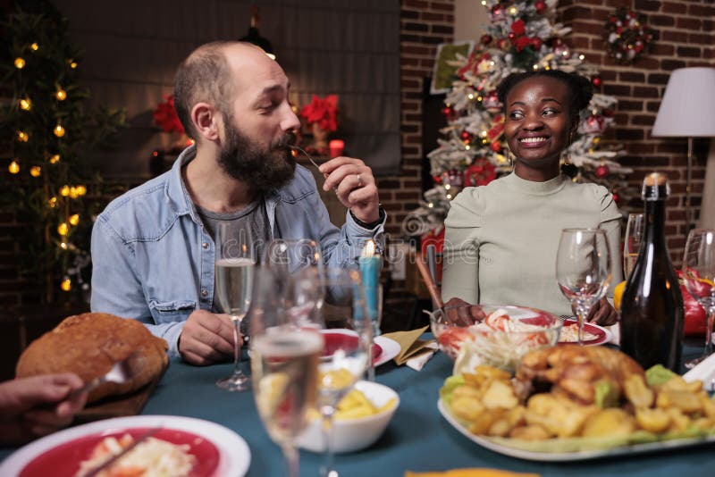 Couple eating, drinking sparkling wine at christmas dinner table