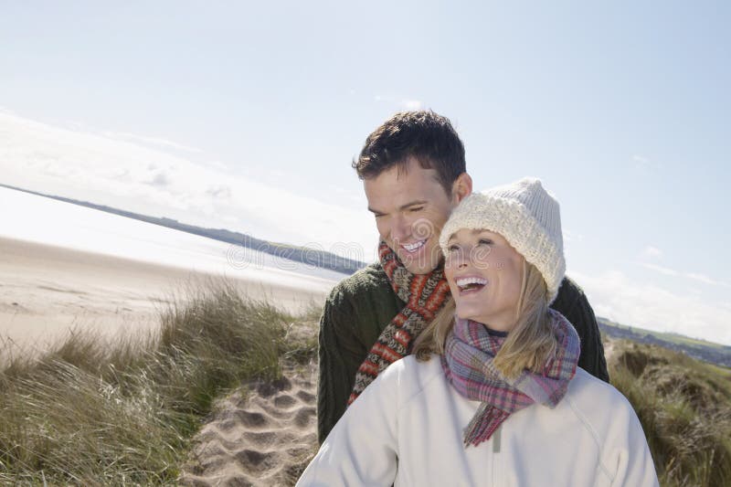 Cheerful young couple in winter clothing embracing on beach. Cheerful young couple in winter clothing embracing on beach