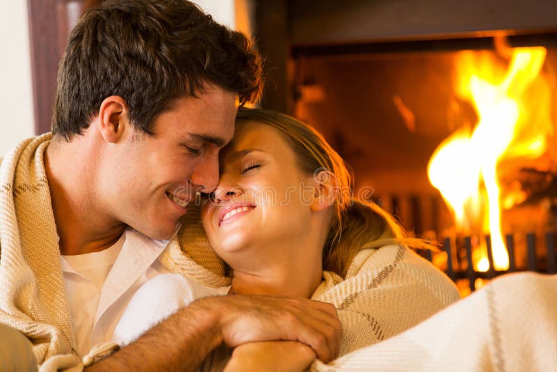 Loving young couple embracing at home next to fireplace. Loving young couple embracing at home next to fireplace