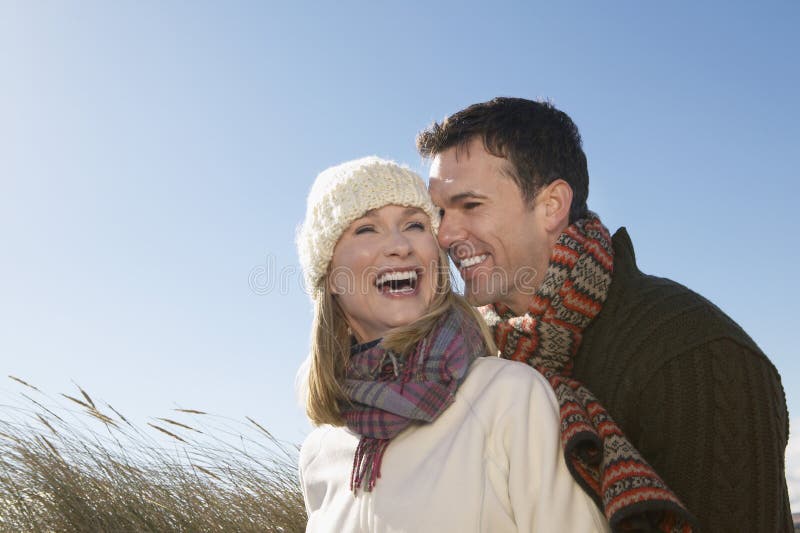 Cheerful couple in winter clothing embracing outdoors. Cheerful couple in winter clothing embracing outdoors