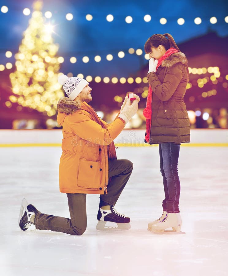 Couple with engagement ring at xmas skating rink