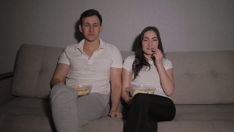 Couple enjoying watching a movie at home laughing on the couch