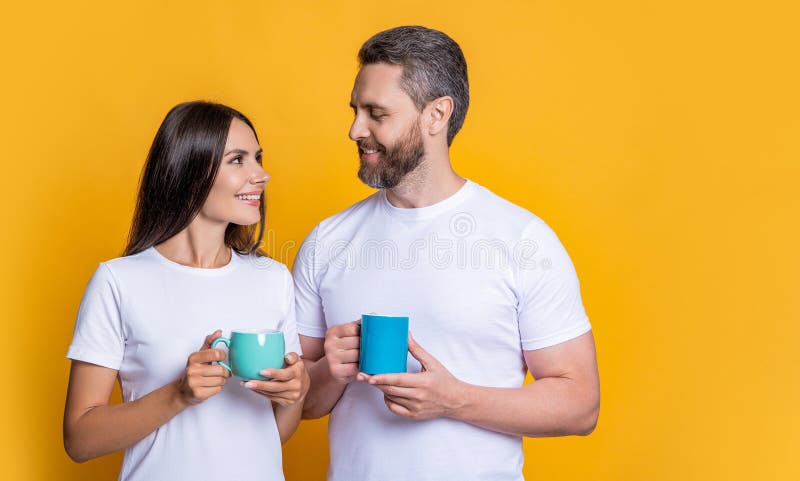 Family couple having coffee isolated on yellow. Morning coffee time. Couple of man and woman drinking tea. Family day together. Warm relationship. Coffee break at home. Togetherness. Family couple having coffee isolated on yellow. Morning coffee time. Couple of man and woman drinking tea. Family day together. Warm relationship. Coffee break at home. Togetherness.