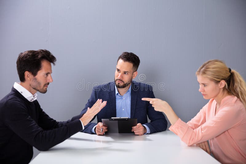 Couple Fighting In The Lawyer Office. Unhappy Married Couple Get Divorced Arguing And Fighting In Front Of Male Lawyer In Office