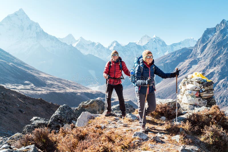 Couple following Everest Base Camp trekking route near Dughla 4620m. Backpackers carrying Backpacks and using trekking poles and