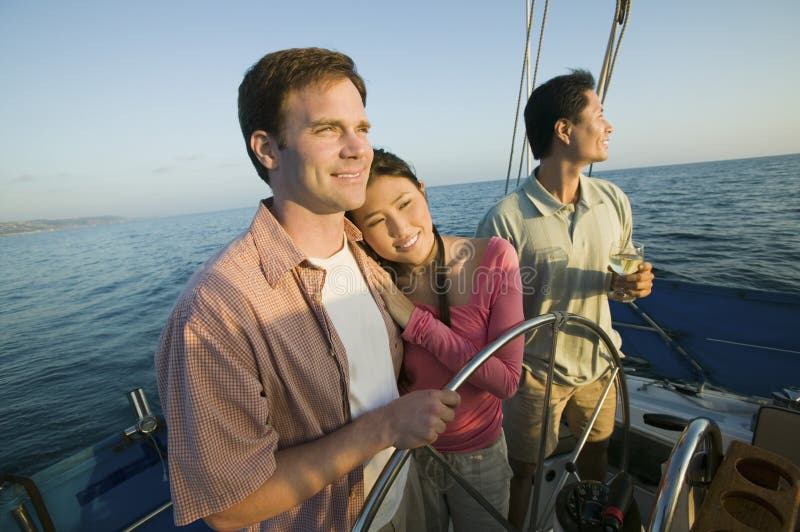 Couple with friend at steering on yacht