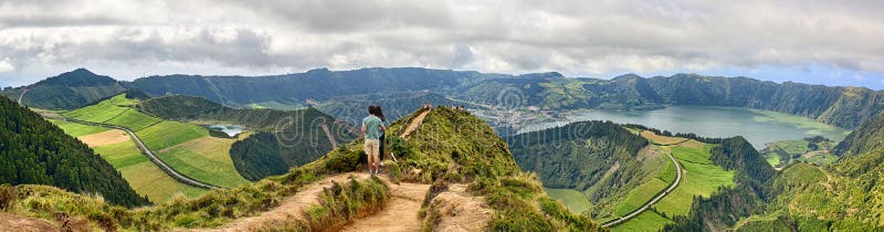 Young couple enjoy the panoramic view of Crater Sete Cidades from Pico da Cruz at Sao Miguel, Azores. Young couple enjoy the panoramic view of Crater Sete Cidades from Pico da Cruz at Sao Miguel, Azores