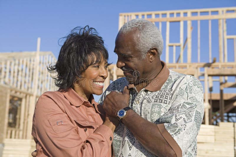Happy loving senior African American couple in front of incomplete house