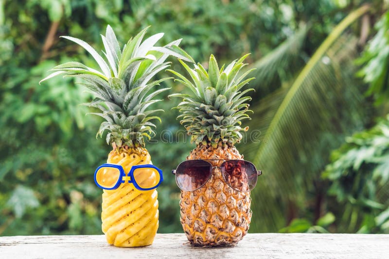 Couple of funny attractive pineapples in glasses and glasses for swimming on a tropical terrace. tropical island