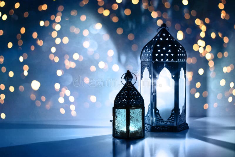 Couple of glowing Moroccan ornamental lanterns on the table. Greeting card, invitation for Muslim holy month Ramadan stock photo