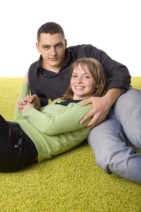 Izolované na bielom mladý pár, ktorý leží na zelený koberec.