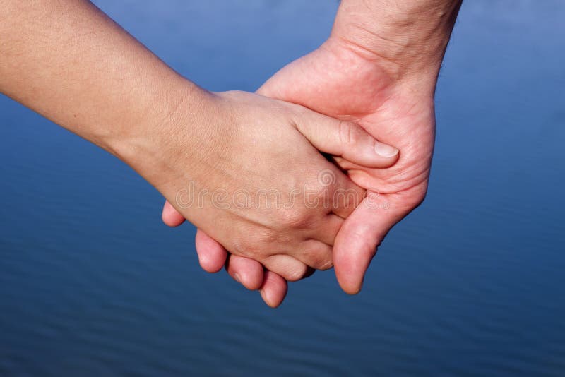 Couple hands over blue lake