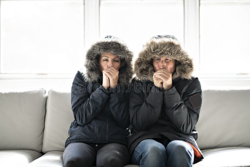 Couple have cold on the sofa at home with winter coat stock images
