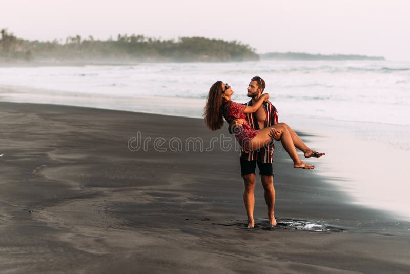 A Man Holds A Woman With Her Legs Engulfing His Waist And She Laughs  Joyfully Towards The Ocean. High Quality Photo Stock Photo, Picture and  Royalty Free Image. Image 164446145.