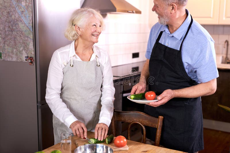 senior caucasian couple having fun in kitchen with healthy food, cooking meal at home stock photography
