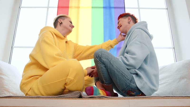 Couple heureux célébrant la fierté à la maison embrassant l'amour et la convivialité dans un cadre coloré banque de vidéos