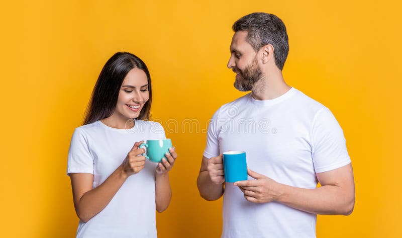 Couple of man and woman drinking tea. Family day together. Warm relationship. Coffee break at home. Family couple having coffee isolated on yellow. Morning coffee time. Deep conversation. Couple of man and woman drinking tea. Family day together. Warm relationship. Coffee break at home. Family couple having coffee isolated on yellow. Morning coffee time. Deep conversation.