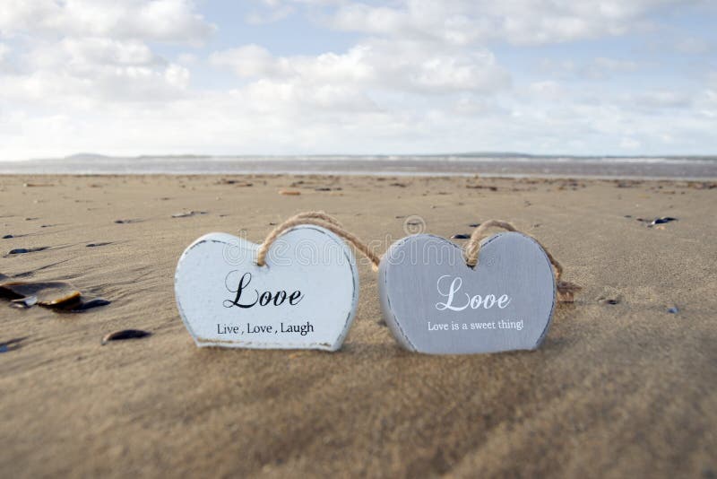 Couple of inscribed wooden love hearts in the sand