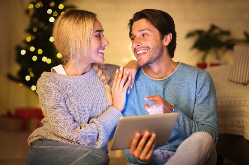 Couple joyeux choisir un film sur tablette le soir de noël photo stock
