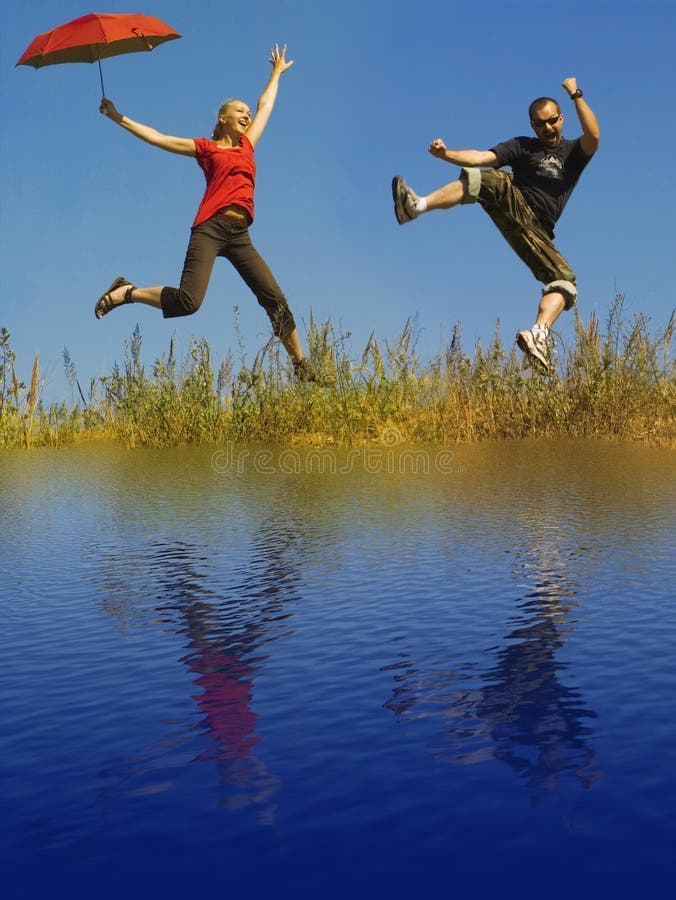 Man and woman jumping on a meadow - water reflection. Man and woman jumping on a meadow - water reflection