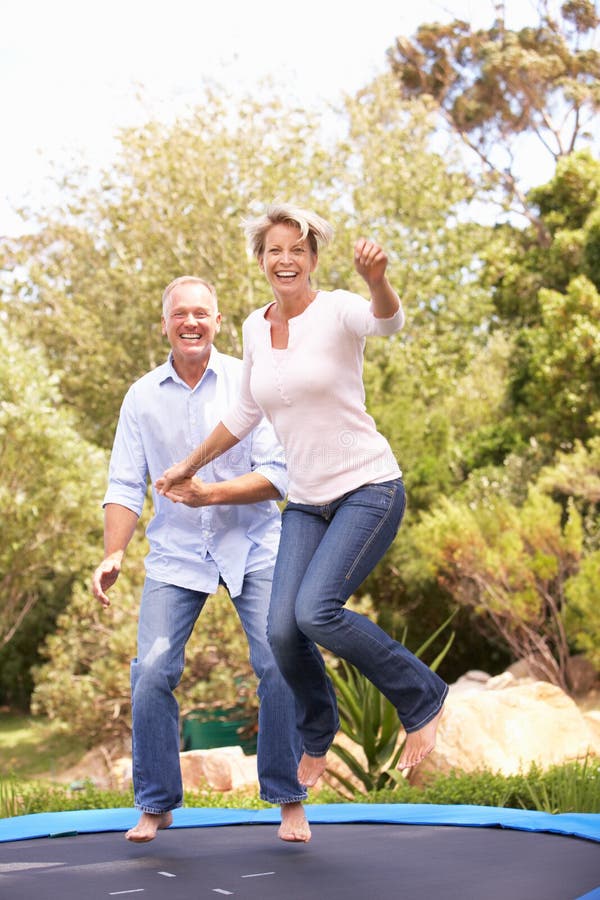 Couple Jumping On Trampoline In Garden royalty free stock photography Couple Jumping On Trampoline In Garden royalty free stock photography