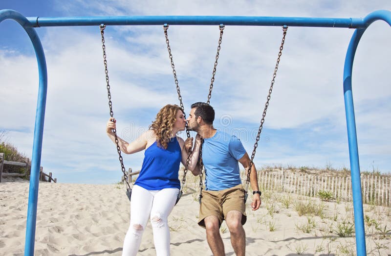 Couple kissing on swings.