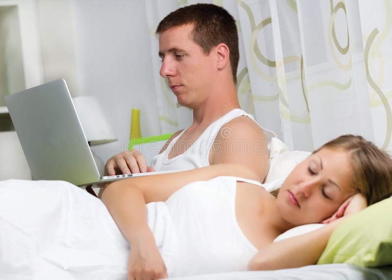 Couple with laptop in bed