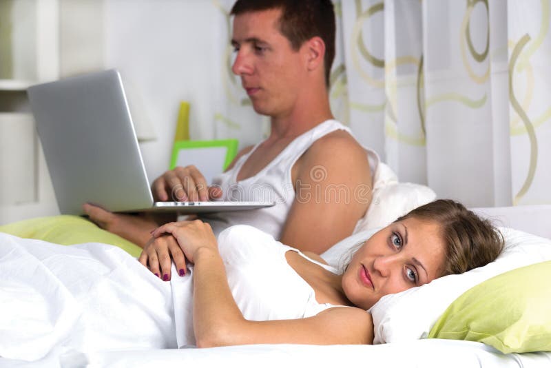 Couple with laptop in bed
