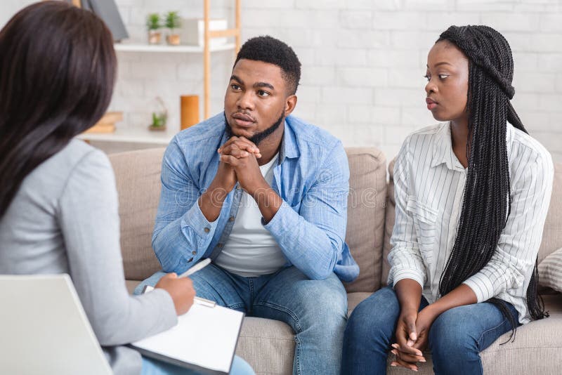 Couple Listening To Counselor`s Advice Sitting On Sofa During Therapy Session Stock Image