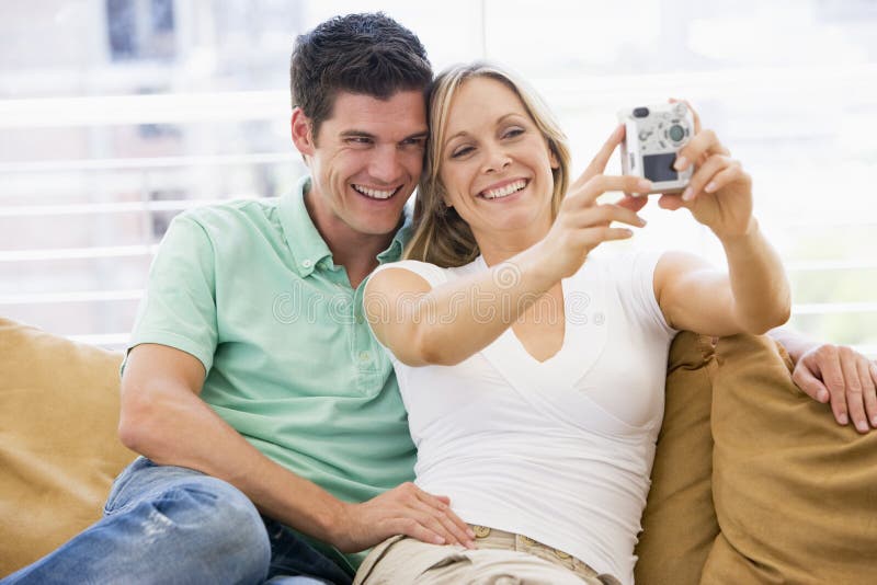 Couple in living room with digital camera smiling