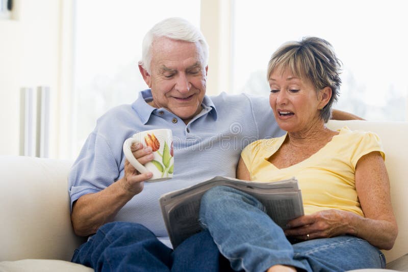 Couple in living room reading newspaper