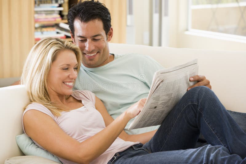 Couple in living room reading newspaper