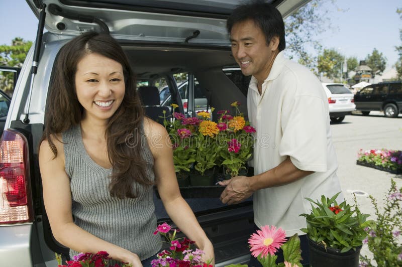 Woman with husband Loading flowers into back of SUV, portrait. Woman with husband Loading flowers into back of SUV, portrait