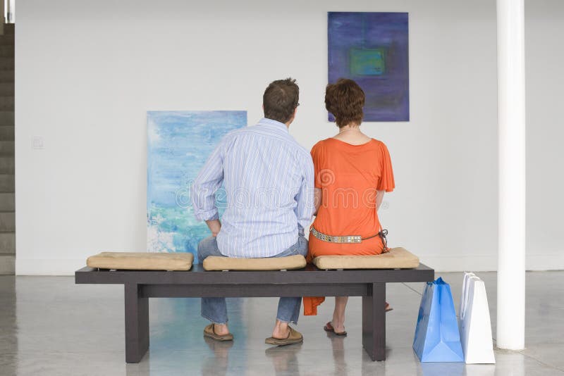 Couple Looking At Paintings In Art Gallery