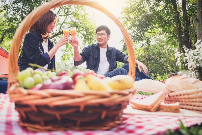 Couple in love drink a orange juice and fruits on summer picnic, leisure, holidays, eating, people and relaxation concept