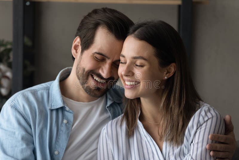 Beautiful Couple In Love Embracing Sit On Sofa At Home Stock Image