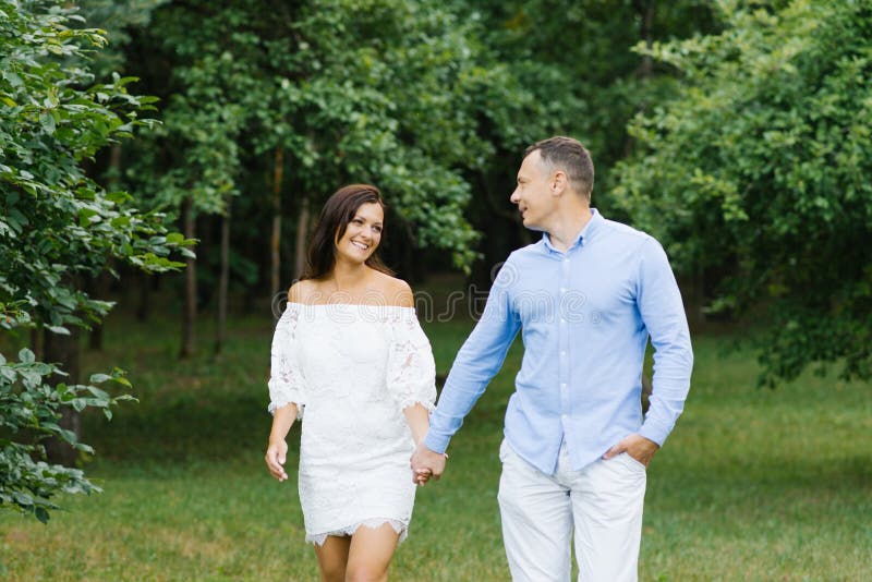 A couple in love, a guy and a girl holding hands, walking in the Park and smiling at each other royalty free stock photos A couple in love, a guy and a girl holding hands, walking in the Park and smiling at each other royalty free stock photos