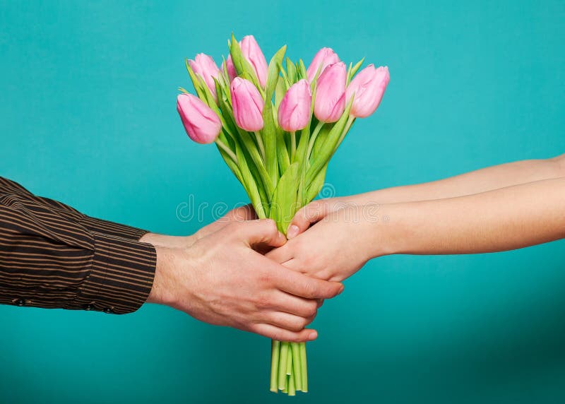 Couple in love holding a bouquet of tulips on a blue background. The concept of Valentine's Day.