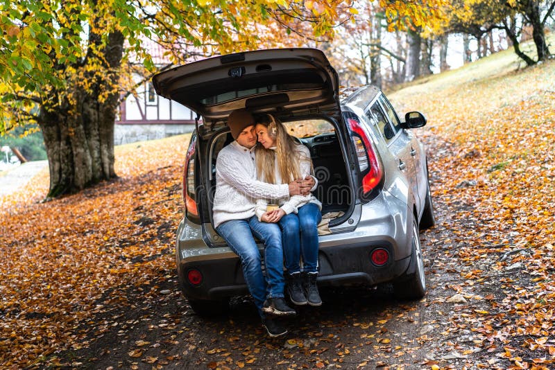 Couple in love. Road trip. A guy and a girl are sitting in the open trunk of a car.